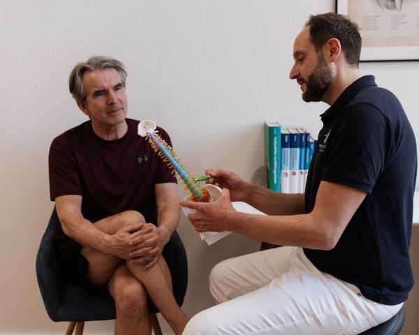 Benjamin Zimmermann erklärt anhand eines Wirbelsäulenmodells mögliche Ursachen für die bestehenden Probleme